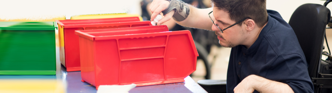 young man in a wheelchair sorting things into colored bins