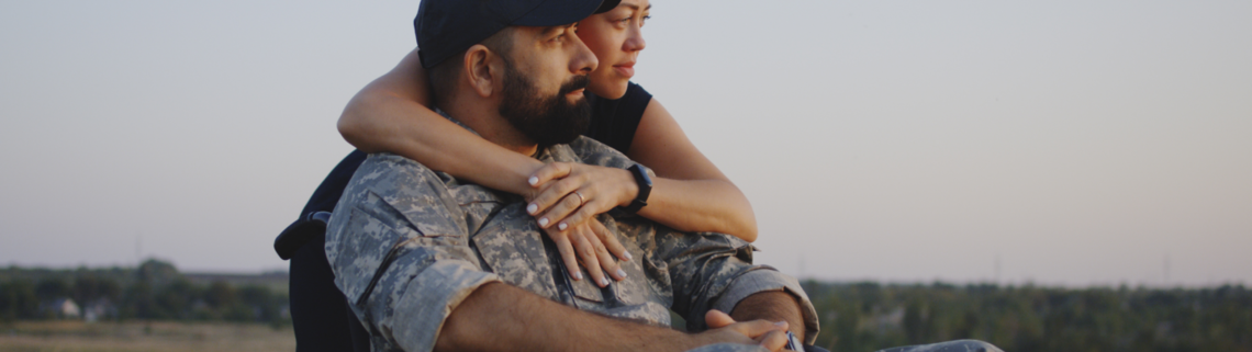 veteran man in a wheelchair being embraced by a woman